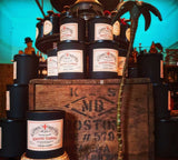 Collection of exotic cargo coconut wax candles with visible labels on a wooden crate against a teal background